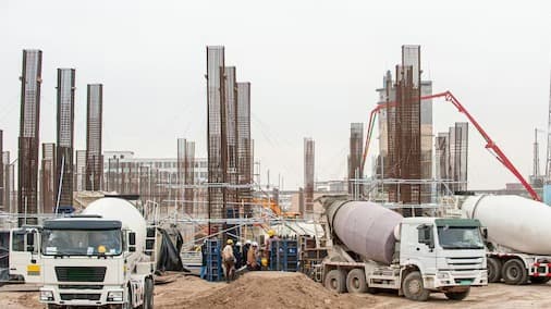 Construction site with concrete mixer trucks and rebar columns during a building's foundation phase
