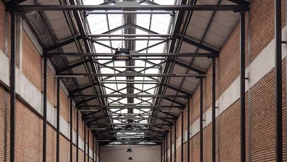Industrial skylight corridor with exposed steel roof trusses and brick walls